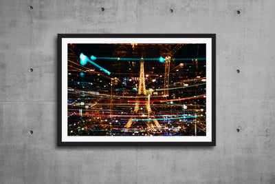 A vibrant framed and matted artwork of Eiffel Tower by Jeremiah Alley is on a concrete wall